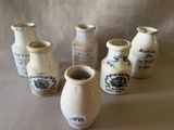 plusieurs vases blancs portant des inscriptions noires, posés sur une table