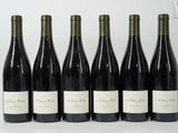 six bottles of wine are lined up on a white surface