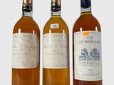 trois bouteilles de vin posées les unes à côté des autres sur une surface blanche