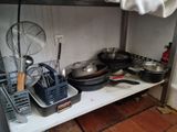 de nombreuses casseroles et poêles sur une étagère dans la cuisine