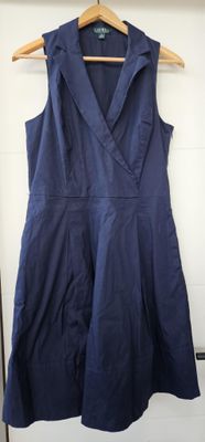 une robe bleue sans manches suspendue à un cintre devant un mur blanc