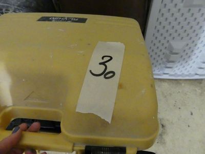 une personne tenant une mallette jaune sur laquelle est collé un autocollant