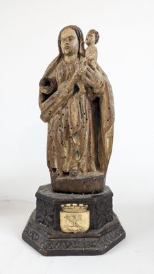 une vieille statue représentant une femme tenant un enfant dans ses bras, posée sur un piédestal