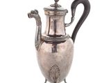 silver plated coffee pot with a black handle on a stand