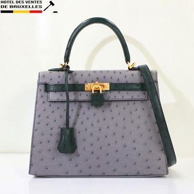 Le sac à main en cuir d'autruche gris et vert est posé sur une surface blanche.