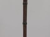an old wooden flute with a black handle on a clear surface