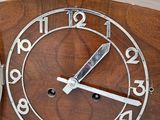a wooden clock with a silver face on a white background