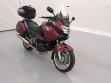une moto rouge garée dans une pièce aux murs blancs