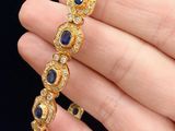 a close up of a person holding a gold bracelet with blue stones