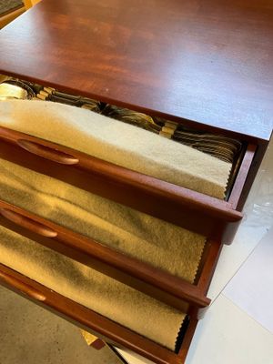 une commode en bois à trois tiroirs, sur laquelle est posé un tapis