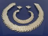 un ensemble composé d'un collier et de boucles d'oreilles en or, posé sur un fond bleu