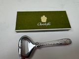 a silver bottle opener with a green box on a table