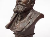 un buste en bronze représentant un homme barbu, posé sur un socle