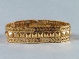 gros plan d'un bracelet en or sur une surface blanche