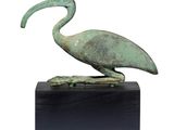 statue représentant un oiseau sur un socle noir, avec un fond blanc