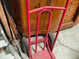 a red hand truck that is sitting in front of a dresser