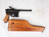 un gros plan d'un pistolet posé sur une surface blanche, avec un étui en bois