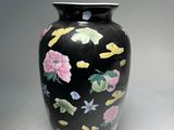a black vase with a floral design on it