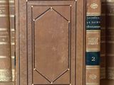 de nombreux livres sur une étagère, avec une horloge posée dessus