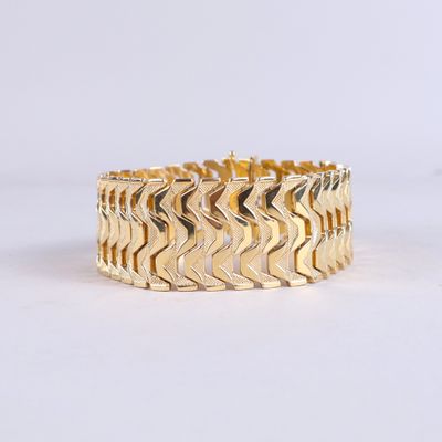 gros plan d'un bracelet en or sur fond blanc