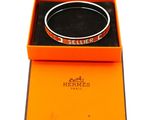 an orange box with a bracelet inside of it on a white surface