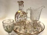 Des bouteilles et des verres sont posés sur un plateau, avec une carafe en arrière-plan.