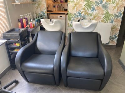 two black chairs in a room with a sink and a mirror