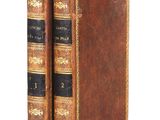 two old books are stacked on top of each other on a white surface
