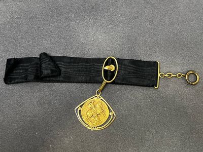 une ceinture noire ornée d'une pièce d'or
