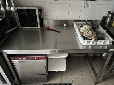 plan de travail en acier inoxydable dans une cuisine professionnelle équipée d'un micro-ondes et d'un lave-vaisselle