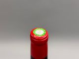 une bouteille de vin rouge avec une étiquette verte sur fond blanc