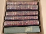 six books in a box that are sitting on a table