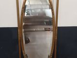 une image représentant un miroir à cadre doré posé sur un pied
