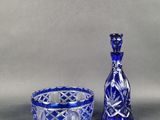 un vase en verre bleu et un bol en verre bleu posés sur une table