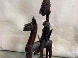 statue en bois représentant un homme à cheval, avec un oiseau sur le dos
