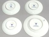 four white plates with blue and white designs on them on a gray surface