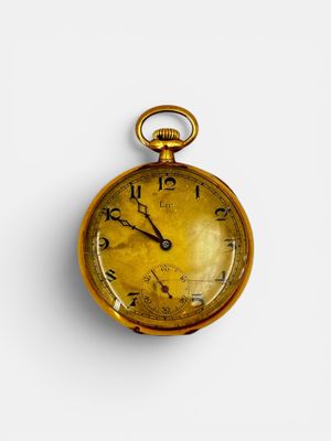 a gold pocket watch on a white surface with a white background