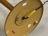 a clock that is sitting on the floor next to a wooden pole