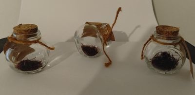 trois petits bocaux en verre remplis de grains de café posés sur une surface blanche