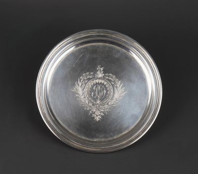an antique silver plate with a crest on it on a black background