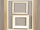 two white frames hanging on a wall with a gray wall behind them
