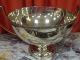 a silver bowl on a marble table with a red curtain in the background