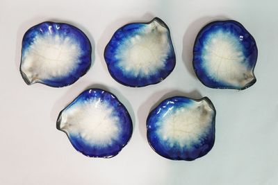 quatre bols bleus et blancs, parsemés de taches blanches, posés sur une surface blanche