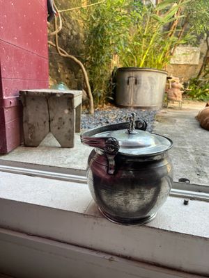 a tea pot sitting on a window sill next to a cat