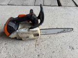 une tronçonneuse orange et noire posée sur un sol en béton