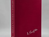 a red book sitting on top of a table next to a white wall