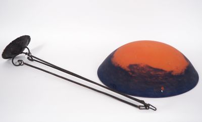 an orange and blue bowl with a black handle on a white surface