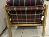 a plaid chair with a wooden frame in a room
