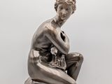 an image of a bronze statue of a woman sitting on a marble base