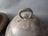 a silver plate with a bell on top of it next to a silver plate with a bell on top